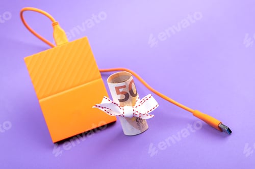 Preview: fifty euro banknote money roll and external portable hard disk drives on purple background