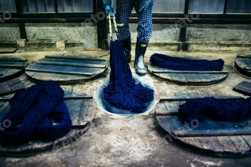Preview: Close up of man beating indigo dye into strands of cotton.