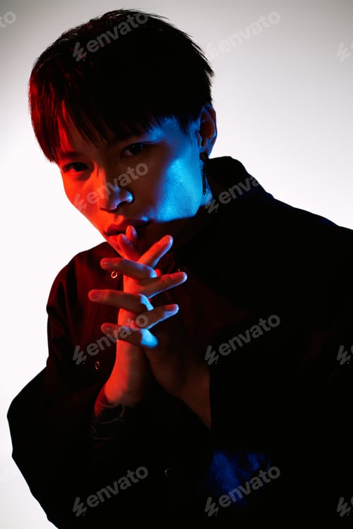 Preview: Stylish young man in creative lighting poses while expressing mystery and allure