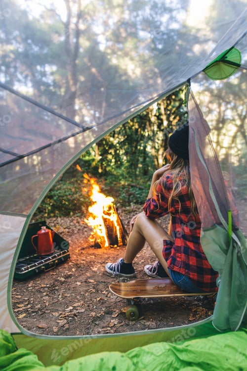 Preview: Camper sitting on a skateboard by the fire