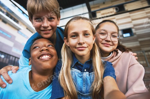 Preview: Four happy adolescent boys and girls taking selfie outdoors