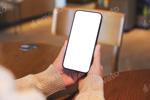 Preview: Mockup image of a woman holding and using mobile phone with blank desktop screen in cafe