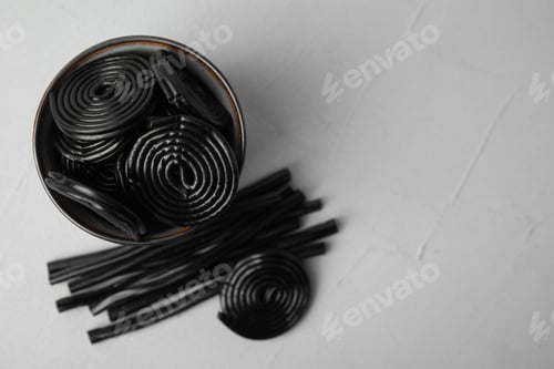 Preview: Tasty black liquorice candies on grey table, flat lay. Space for text