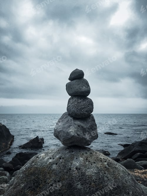 Preview: A pile of balanced stones on a moody seashore