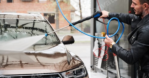 Preview: Young man washing car on carwash station outdoor
