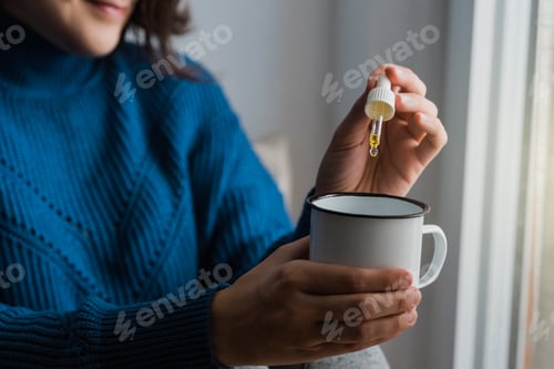 Preview: Woman taking Cannabis cbd oil inside tea cup - Alternative medicine, vitamins and supplements