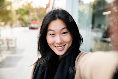 Preview: happy young smiling woman taking a self portrait photo in the city - portrait of young japanese