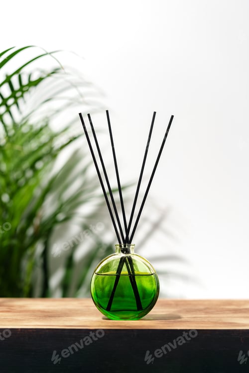 Preview: Green Glass Reed Diffuser On Wooden Tabletop With Greenery In Background