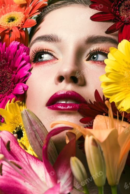 Preview: close-up portrait of attractive young woman surrounded with various flowers looking up
