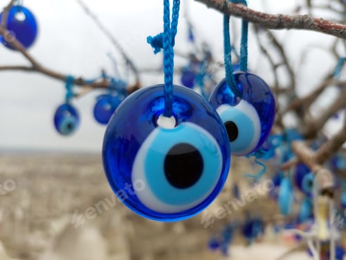Preview: Closeup of tree with multiple blue evil eye charms hanging from it