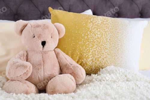 Preview: Cute teddy bear sitting on bed indoors. Space for text