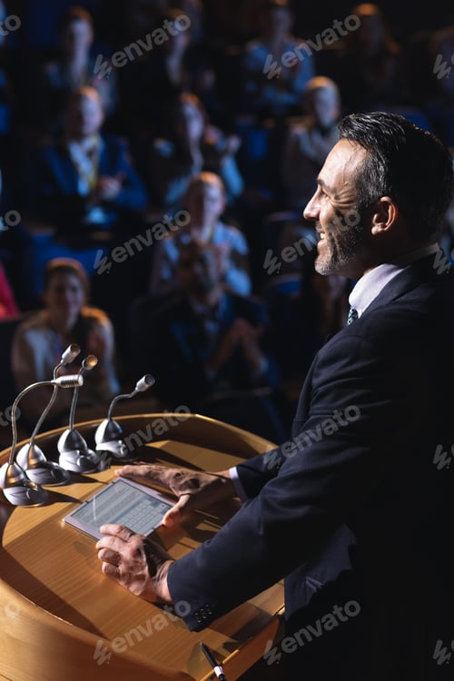 Preview: Side view of Caucasian businessman standing and giving presentation in the auditorium