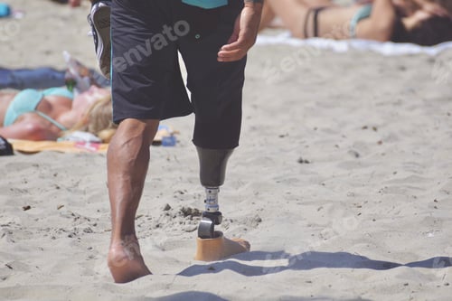 Preview: Young, man with prosthetic lower leg and foot, walking on the beach on a sunny day