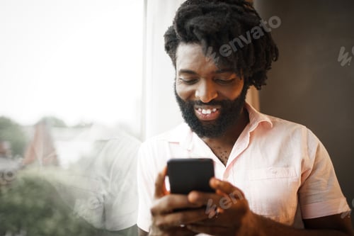 Preview: Bearded young african american man looking at his smartphone