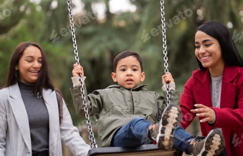 Preview: Portrait of hispanic lesbian couple having fun with their son on a swing