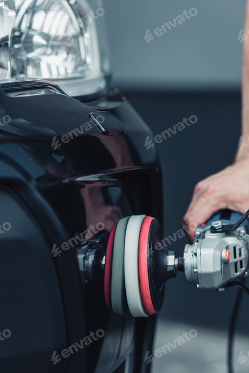 Preview: cropped view of car cleaner polishing car with buffer machine