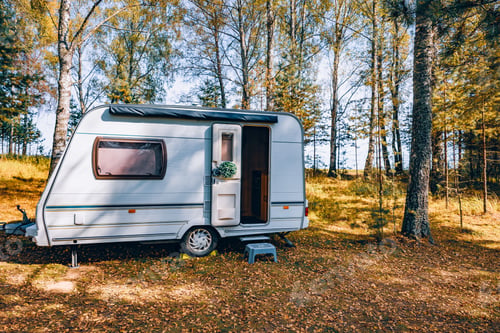 Preview: Camping caravan rv in autumn fall landscape. Caravan trailer in a golden tree forest.