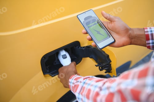 Preview: A african american man stands next to electric delivery van at electric vehicle charging stations