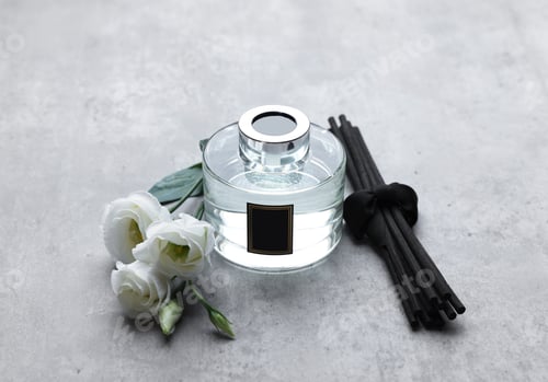 Preview: Reed sticks, glass bottle with aromatic liquid and eustoma flowers on gray marble table