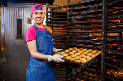 Preview: A professional baker girl is holding a tray with fresh cookies in her hands. Sweet pastries