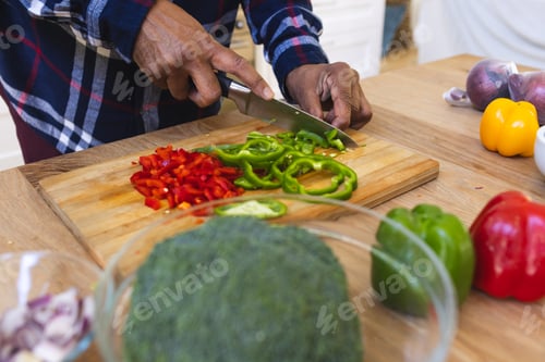 Preview: Hands of african american senior man slicing peppers, chopping vegetables in kitchen