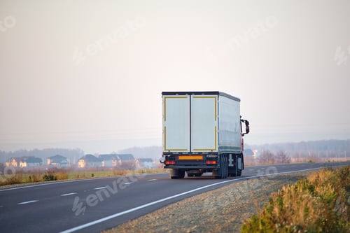 Preview: Semi-truck with cargo trailer driving on highway hauling goods in evening.