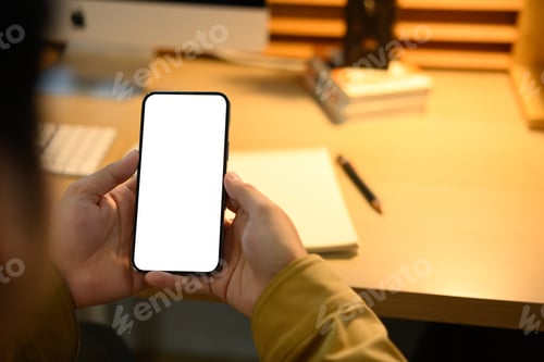 Preview: Close up of man hands holding mock up smart phone with modern workspace