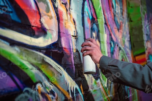 Preview: cropped view of street artist painting graffiti with aerosol paint on wall at night