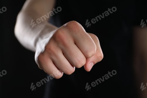 Preview: Man showing fist with space for tattoo on black background, selective focus