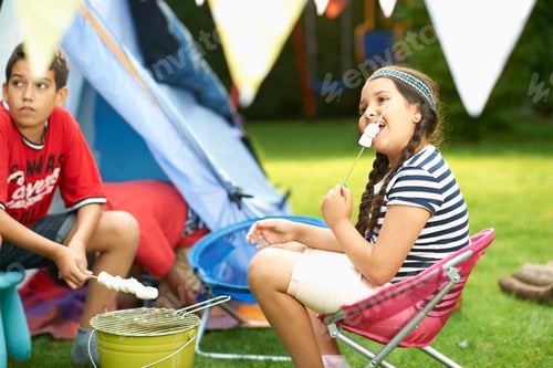 Preview: Sister and brother toasting marshmallows in front of homemade tent in garden