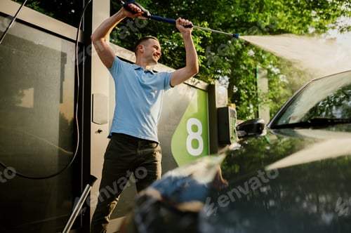 Preview: Man holds high pressure water gun, car wash
