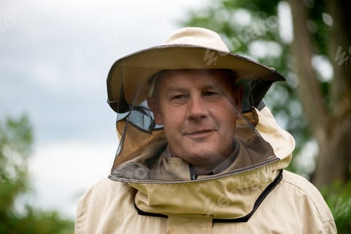 Preview: The smiling beekeeper stands near apiary. Apiculture. Apiary.