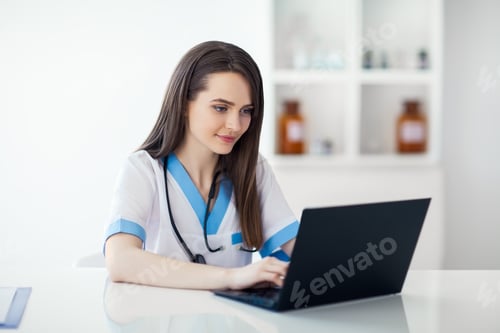 Preview: Beautiful doctor working on laptop in hospital