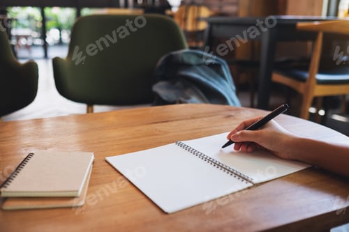 Preview: Closeup image of a woman writing on a blank notebook on the table