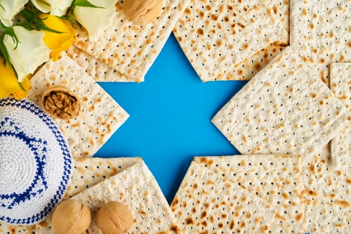 Preview: Passover celebration concept. Blue Star of David made from matzah, white and yellow roses, kippah an