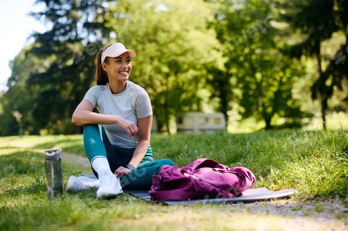 Preview: Happy athletic woman relaxing after exercising in the park.