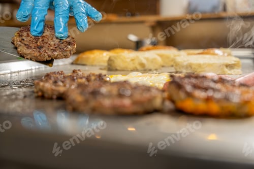 Preview: Cook preparing a delicious hamburger on a hot grill