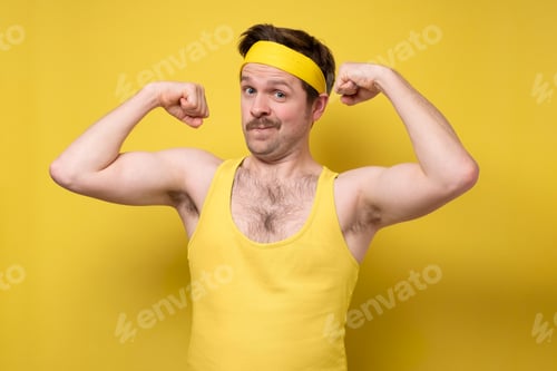 Preview: Young man showing arms muscles smiling being proud.