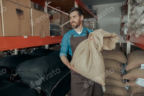 Preview: Warehouse worker with bag of fresh roasted coffee on small factory