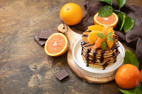 Preview: Delicious bananas pancakes with chocolate and red oranges on rustic table. Copy space.