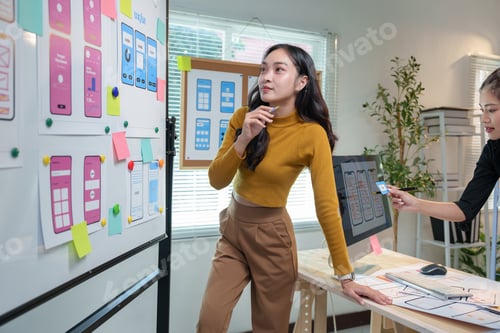 Preview: Two female web designers are discussing ux/ui design for a new mobile application, analyzing wirefra