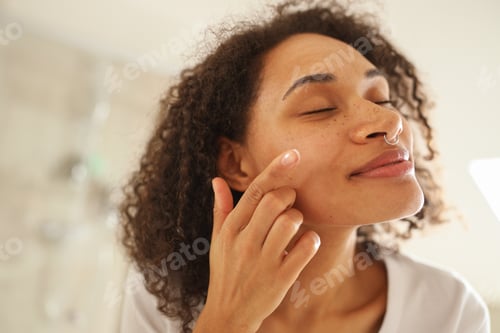 Preview: Woman applying lotion to her Forehead, Cheek, and Neck in front of mirror