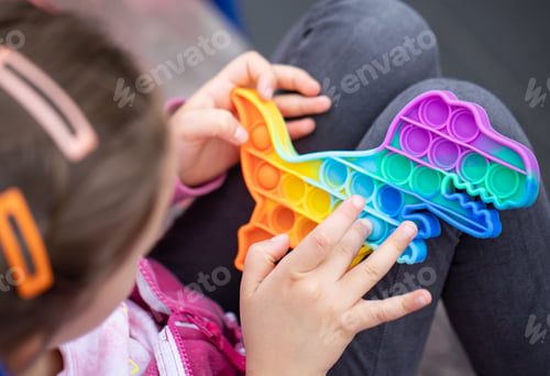 Preview: Close-up of a trendy toy pop it in the hands of a little girl.