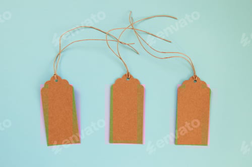 Preview: Brown blank paper price tags or labels set on the blue background, top view.