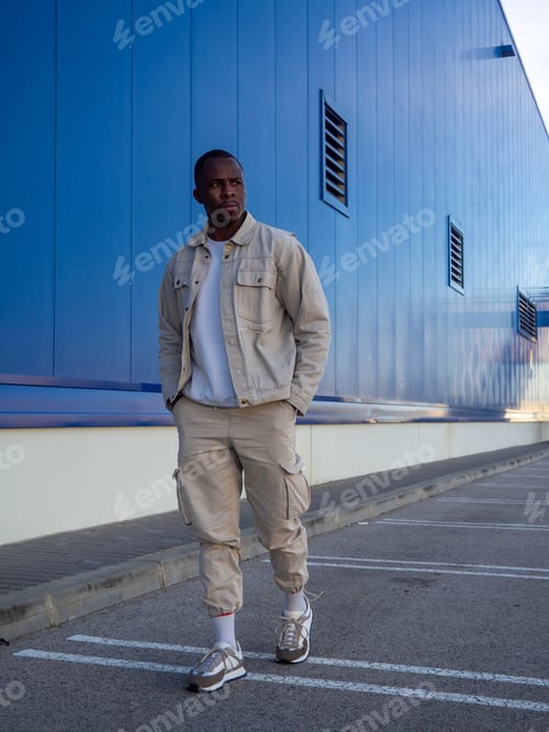 Preview: Fashionable black Spanish male posing against a blue wall