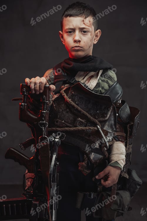 Preview: Armed with shotgun kid poses in dark background looking at camera