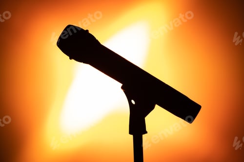 Preview: Silhouette of a microphone illuminated by bright orange light