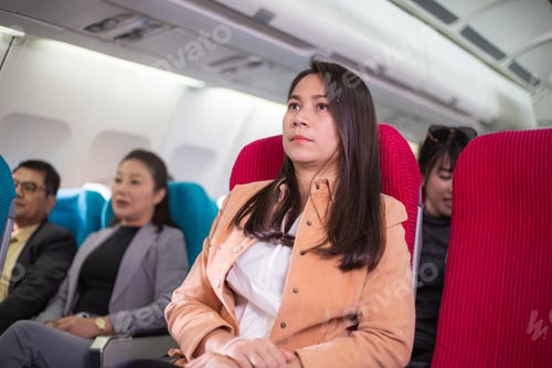 Preview: Group of passengers sitting at seat on airplane during flight.