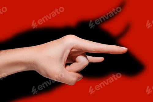 Preview: Male hand shows the gesture of a goat in profile. Shadow in the form of a Bull,