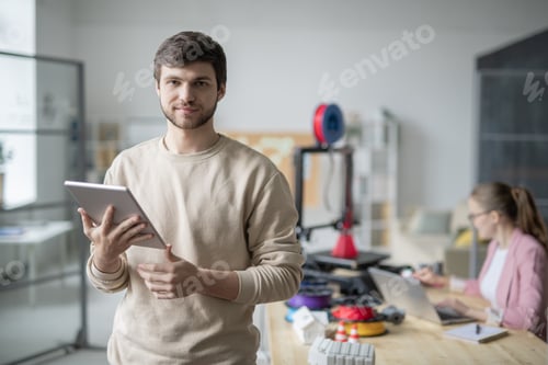 Preview: Businessman with touchpad on background of colleague working with 3d printer